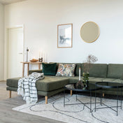 Modern living room with a green sectional sofa, coffee table, and decorative items.