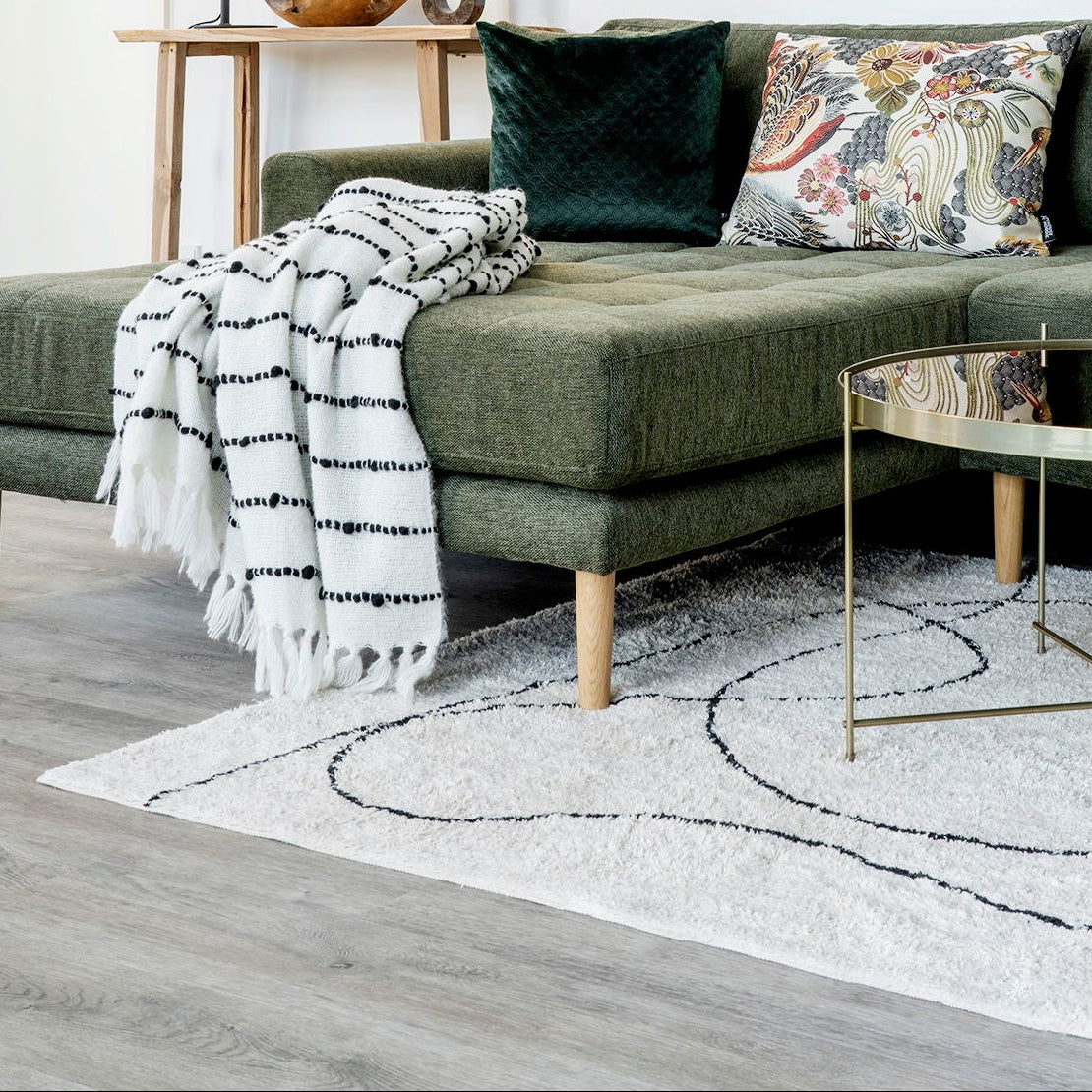 Modern living room with a green sofa, decorative pillows, and a coffee table.
